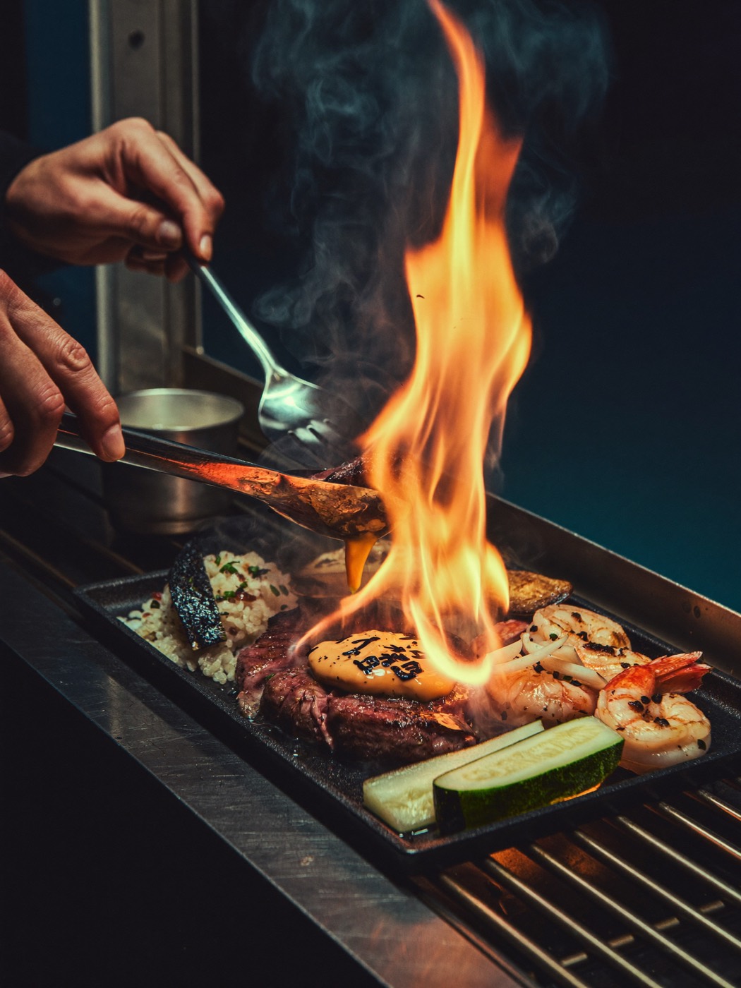 A sizzling hibachi plate finished over open flame at a food truck